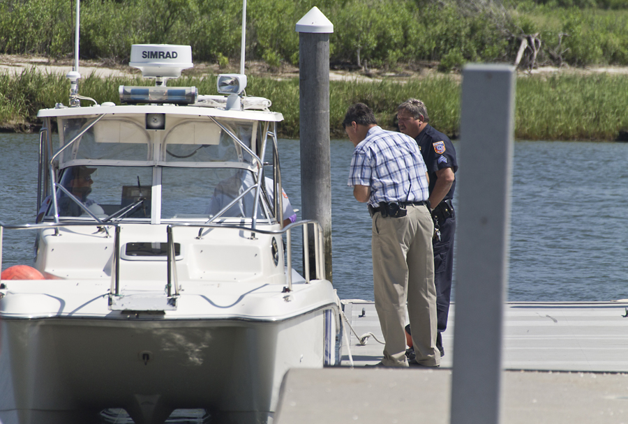 Southold Town police sergeants confer with town marine unit officers after they arrived in Mattituck about noon Monday with the crash victim's body on board. (Credit: Paul Squire)
