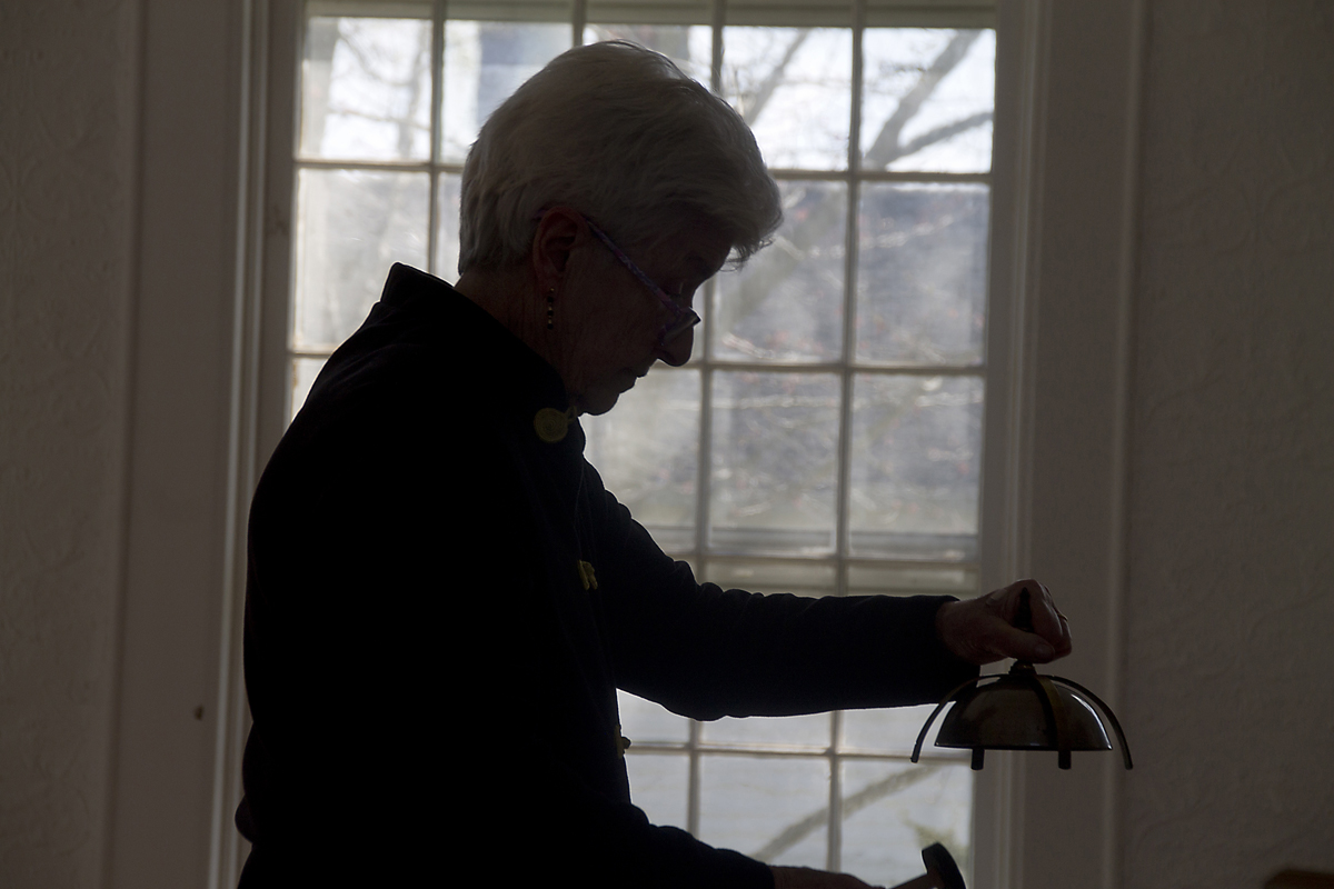 Musical Director Patsy Rogers plays a clock bell during one of the orchestra's songs. (Credit: Paul Squire)