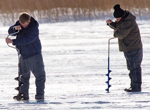 Two ice fishermen hard at work, drilling holes in the ice atop Great Pond in Southold. (Credit: Garret Meade)
