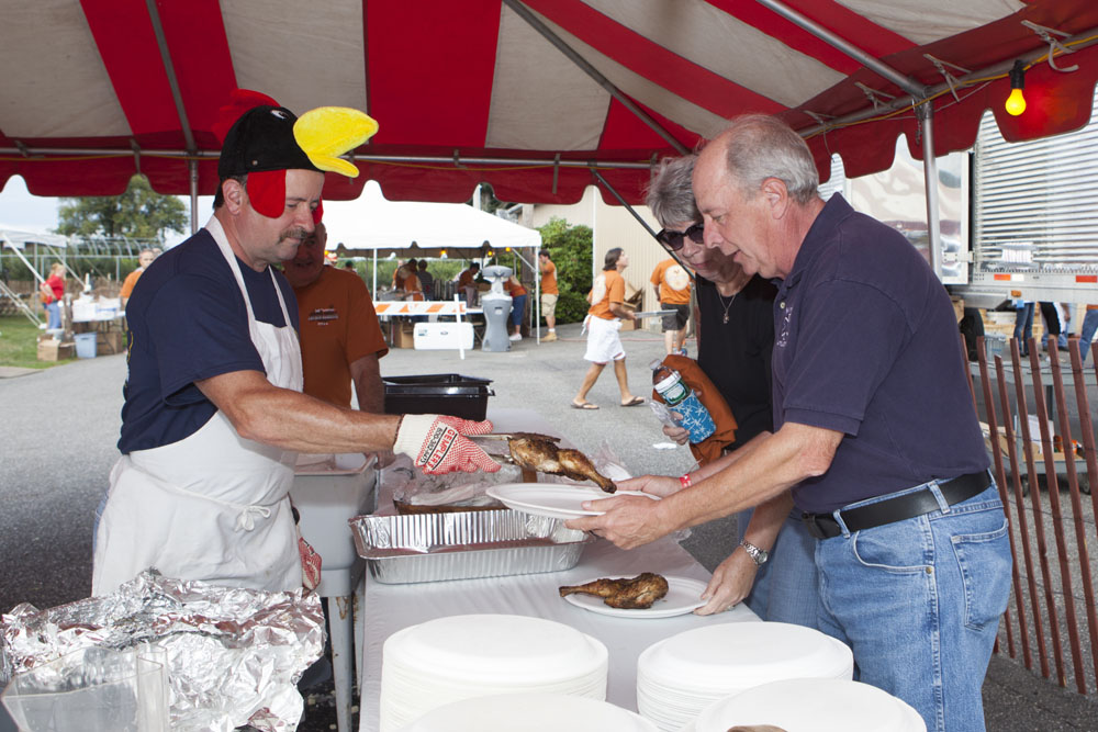Wearing his traditional chicken hat, Tom Shelby serves Larry and Pat Speciner of Middle Island. (Credit: Katharine Schroeder)