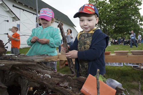Dillon Realander, 2, of Riverhead helps construct a fairy house. His sister Summer, 5, is in the background. (Credit: Katharine Schroeder)