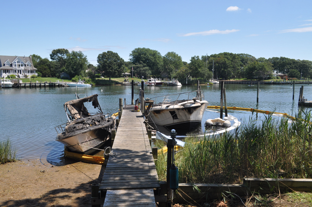 A smaller boat (left) was destroyed after the engine to a yacht (right) caught fire Saturday night on the edge of Gull Pond in Greenport. (Credit: Grant Parpan)
