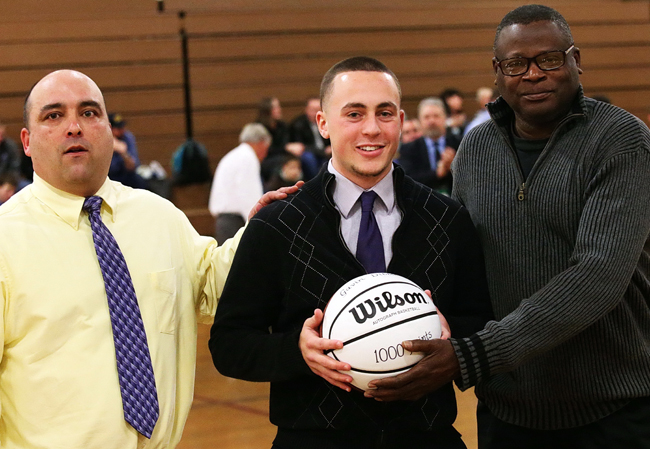 Greenport's Gavin Dibble, a freshman at the University of New Hampshire, was honored before Friday's game for scoring 1,000 career points. Varsity coach Ev Corwin (left) and former coach Al Edwards presented Dibble with a basketball. (Credit: Garret Meade)
