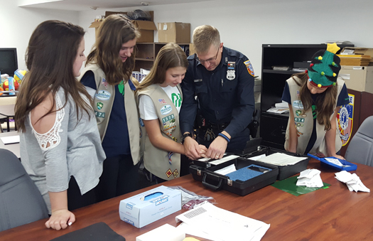 Girl Scout Ainsley Brewer gets fingerprinted by Southold police officer Bill Brewer as Delaney Hudock, Emily Nicholson and Sidney Brewer watch. The Cadettes were working on their Secret Agent badge. (Courtesy photo)