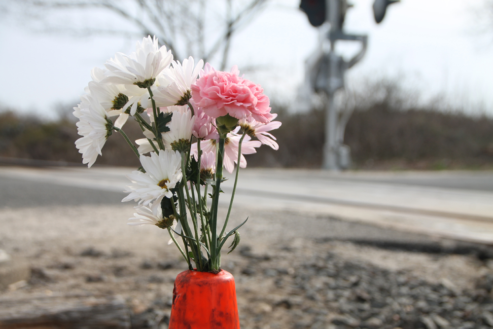 A few flowers stand in a traffic cone set up as an impromptu memorial to Frank McBride at the scene of Tuesday's accident in Mattituck. (Credit: Paul Squire)