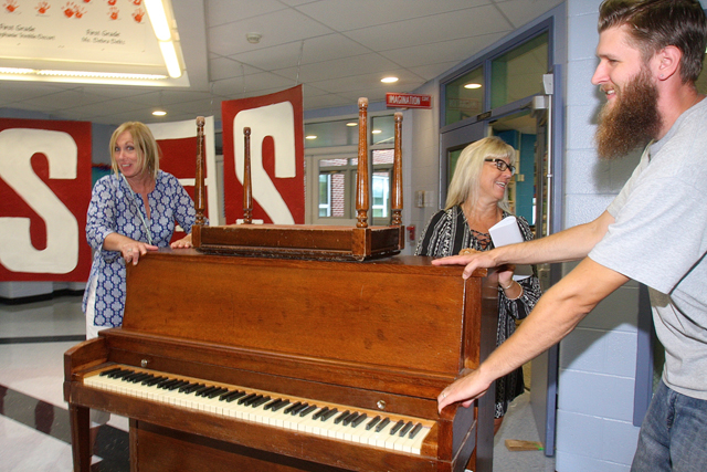 Orchestra teacher Audrey Grathwohl (left), band director Rene Suprina (center) and custodian Drew Averette move a piano to the music room on the first morning of classes.