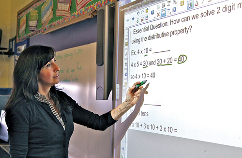 JENNIFER GUSTAVSON PHOTO  |  Our Lady of Mercy teacher Marianne Wachtel works at her classroom's Smartboard.