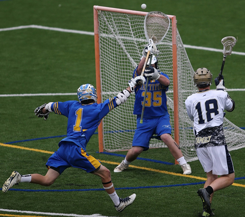 Bayport-Blue Point's Kyle McClancy puts a shot over Alec Durkin's goal. Mattituck/Greenport/Southold's Joe Bartolotto (1) defended on the play. (Credit: Garret Meade)