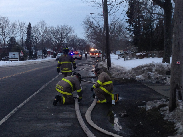 Firefighters clear the hoses from the road after the fire was put out. (Credit: Joe Werkmeister)