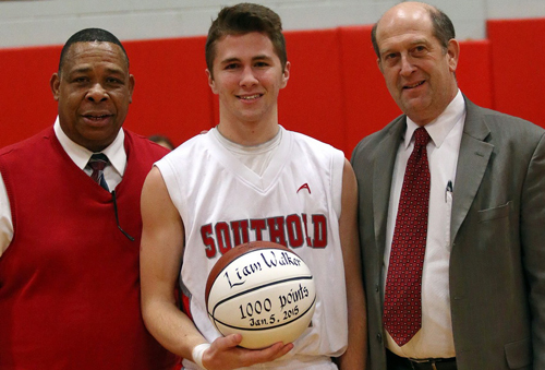 Liam Walker was recognized for recently becoming only the second Southold boy to score 1,000 career points. He was joined by coach Phil Reed, left, and the school superintendent, David Gamberg, in a pregame ceremony in which he was presented with a ball to mark the milestone. (Credit: Garret Meade)