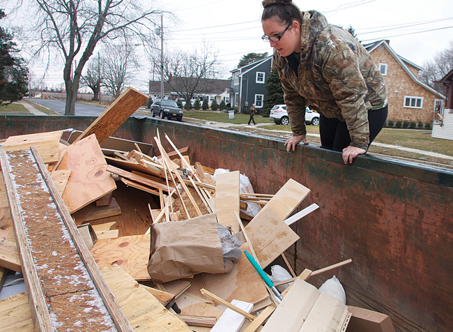 Ms. Horton jumps up on a dumpster looking for metal discarded during a house renovation in Greenport. (Credit: Cyndi Murray)