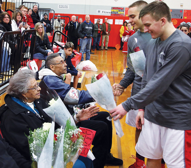 Southold players present flowers to Phil Reed's mother, Laddie, and brother, Elliot, prior to the First Settlers' February game against Shelter Island. (Credit: Garret Meade file)