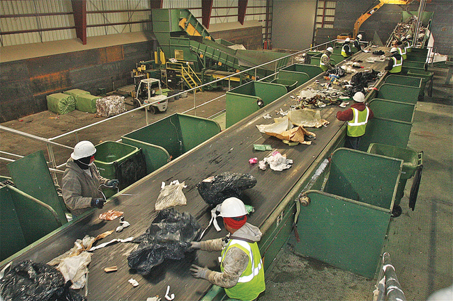 Peconic Recycling workers sort through garbage as it comes down the conveyor belt Monday morning. (Credit: Barbaraellen Koch)
