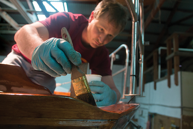 Brewer Yacht Yard & Marina worker Eric Scharpf applies varnish to a Cape Dory-brand sailboat in the Greenport yard’s maintenance area. (Credit: Paul Squire)