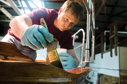 Brewer Yacht Yard & Marina worker Eric Scharpf applies varnish to a Cape Dory-brand sailboat in the Greenport yard's maintenance area. (Credit: Paul Squire)