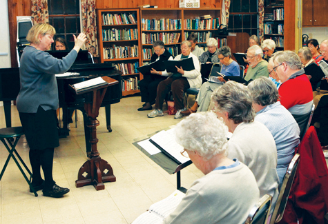 Lois Ross, left, leads the choir at a 2011 practice session of North Fork Chorale. (Credit: file photo)