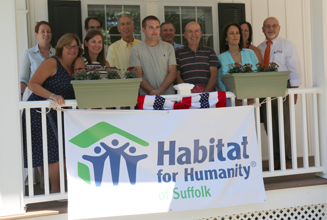 Mr. Bredemeyer, center, stands in front of his new house with the Ruhry family and local business, government and Habitat for Humanity officials Monday.
