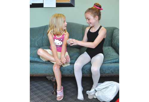 Aela (right) expains the different types of ballet shoes to her 5-year-old sister, Paige. (Credit: Rachel Young)
