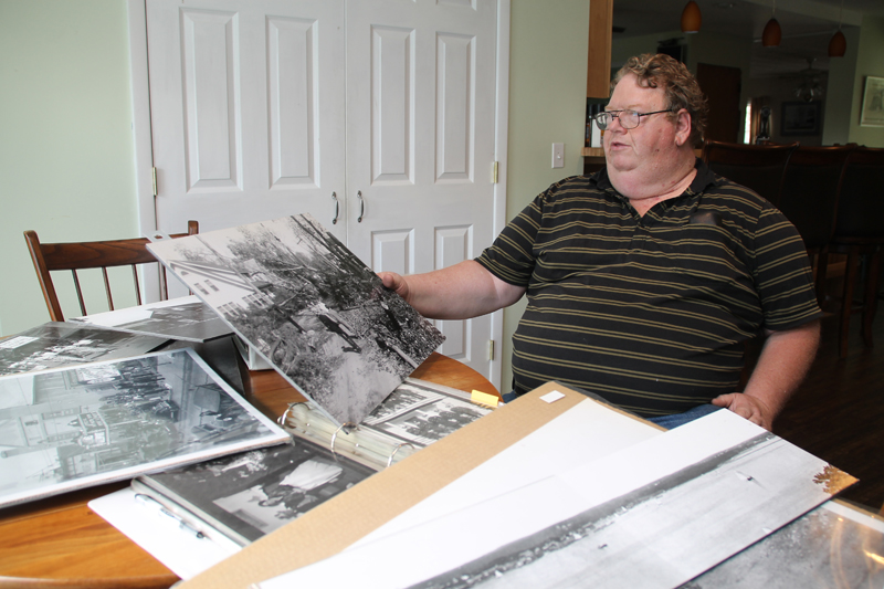 Mike Richter displays a photo taken by Hugo Frey that shows damage caused by the 1938 hurricane. It's one of thousands in his collection of historical photographs of local subjects. (Credit: Paul Squire)