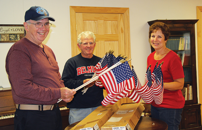 Barbara McAdam (right) sorts flags with the help of her husband, Tom (left), and Cutchogue United Methodist Church Pastor Richie King. Each flag will be fitted with a ribbon bearing a veteran's name and service information. Donations for more than 75 flags have already been collected. (Credit: Carrie Miller)