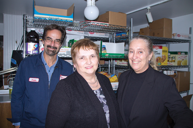 CAST board president Denis Noncarrow (left) stands in CAST's food pantry with incoming executive director Linda Ruland (center) and current executive director Sarah Benjamin, who will become coordinator of the North Fork Parent-Child Program. About 300 families benefit from the food donations. (Credit: Paul Squire)
