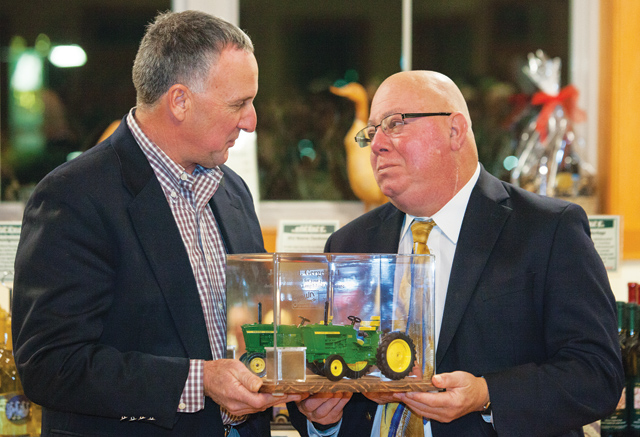 Former Farm Bureau president Mark Zaweski presents Joe Gergela with a miniature tractor as a memento at his retirement party last month. (Credit: Katharine Schroeder, file)
