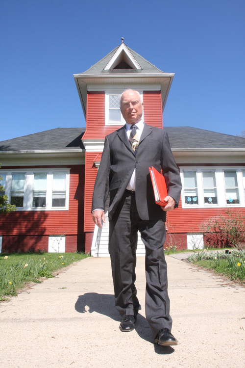 New Suffolk school board president Tony Dill in front of the elementary school. The incumbent is running unopposed this year. (Credit: Barbaraellen Koch)