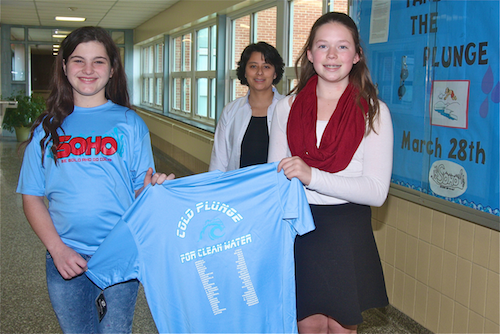 Seventh grade students Amanda Bardsley and Elizabeth Jernick (right) hold up a cold plunge t-shirt as English teacher Emilia Dakis watches on. (Credit: Barbaraellen Koch)