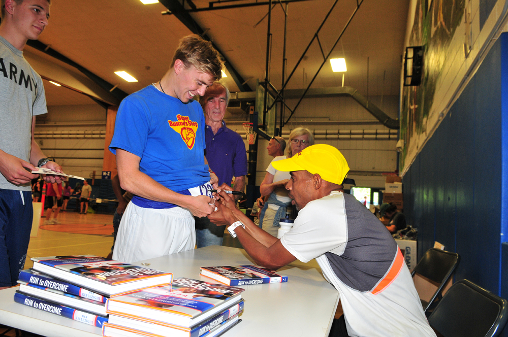 Boston Marathon winner Meb Keflezighi autographs copies of his book prior to the race. (Credit: Bill Landon)