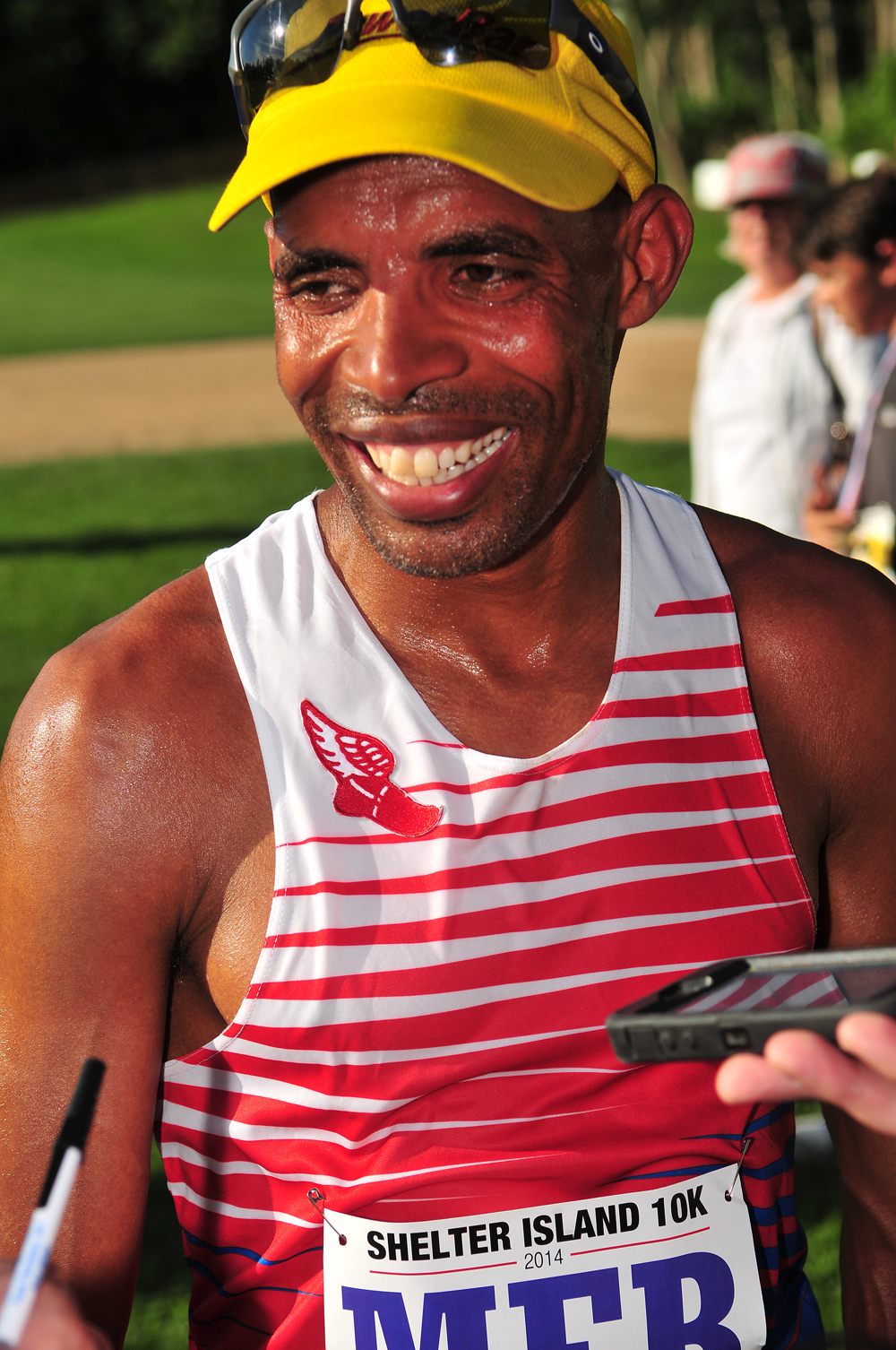 Boston Marathon winner Meb Keflezighi speaks with reporters after crossing the finish line at the Shelter Island 10K Saturday.  (Credit: Bill Landon)