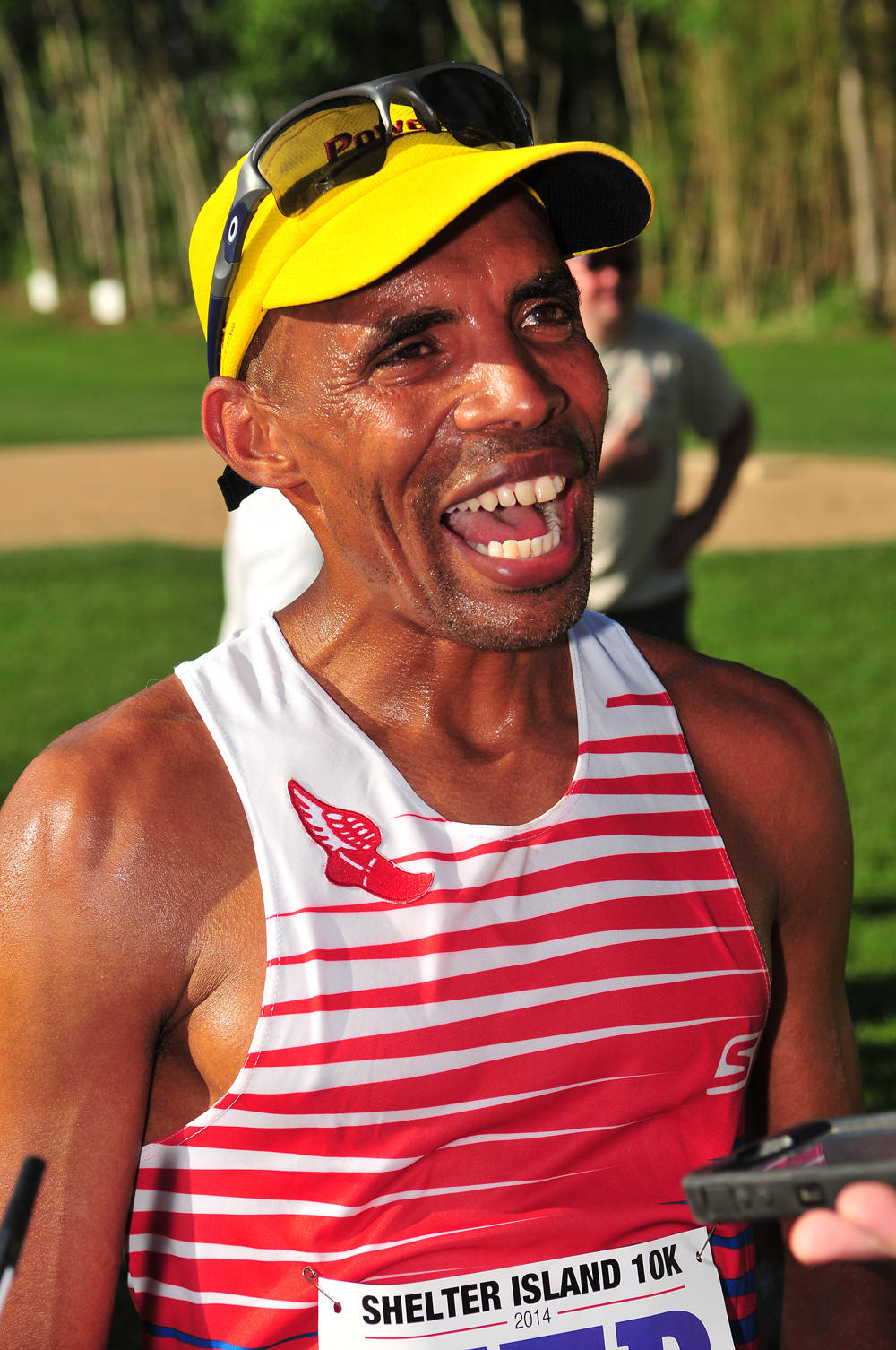 Boston Marathon winner Meb Keflezighi speaks with reporters after crossing the finish line fourth at the Shelter Island 10K Saturday.  (Credit: Bill Landon)