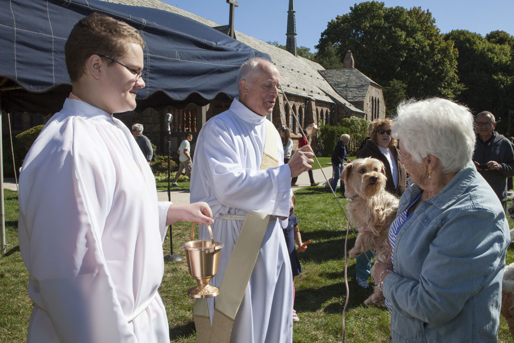 Deacon Sykes, center, blesses Eileen Peters' dog Daisy, age 6, as Chris Massey looks on.