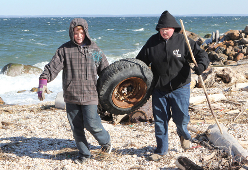 Thirteen-year-olds Connor Whittle, left, and Nicky Mackey remove a discarded tire from the beach.