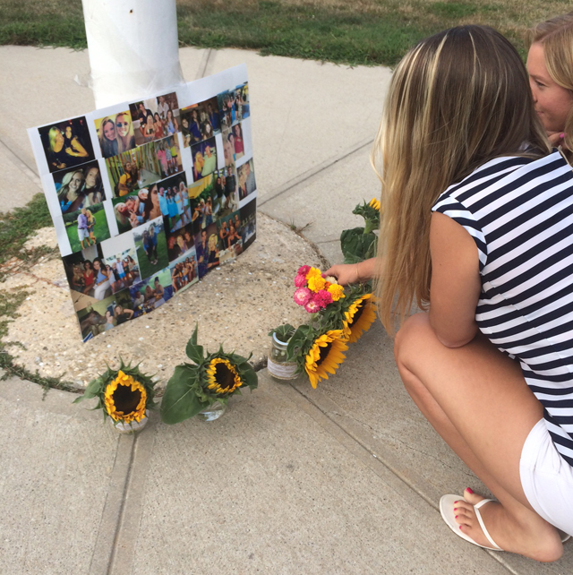 Rebecca Jensen and Megan Drobny, both of Greenport, place flowers at a memorial for Kaitlyn Doorhy outside Mattituck-Cutchogue high School Saturday evening. (Credit: Jessica DiNapoli)