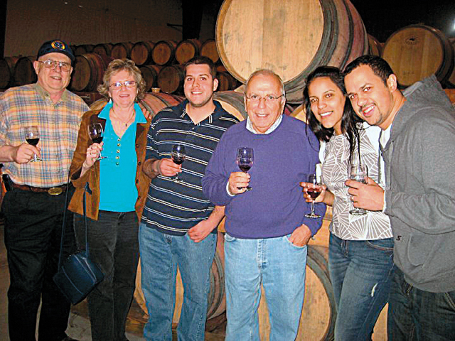 Pindar Vineyards proprietor “Dr. Dan” Damianos (in purple sweater) hosts a barrel tasting and behind-the-scenes tour for Pindar Wine Club members. (Credit: Courtesy photo)