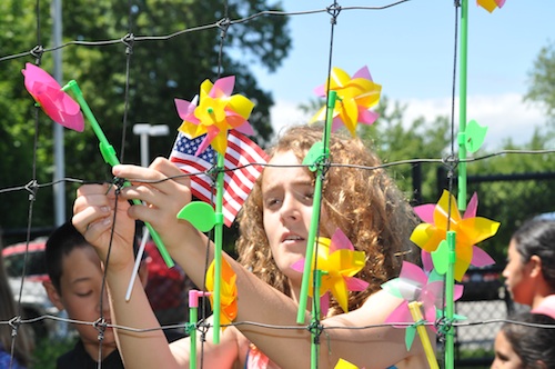 Sixth graders help kindergardeners pin pinwheels to the garden's fence. (Cyndi Murray photo)