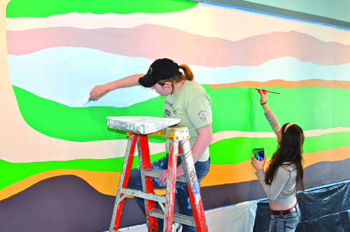 Lauryn Serrano (left) and Mackenzie Robertson were two of six Mattituck High School art students who helped create a mural in the new community room at Veterans Memorial Park in Mattituck. Fellow students Morgan Gildersleeve, Brigid Bozsnyak, Nicole Palladino and Emily Fliss also worked on the abstract painting in a cooperative program between the school and Mattituck Park District.