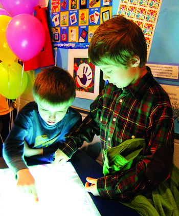 First-grader Quincy Greene (left) and his brother Hudson, a third-grader, draw on a light table at Southold Elementary School's first-ever Art/Science/Technology fair on March 24.